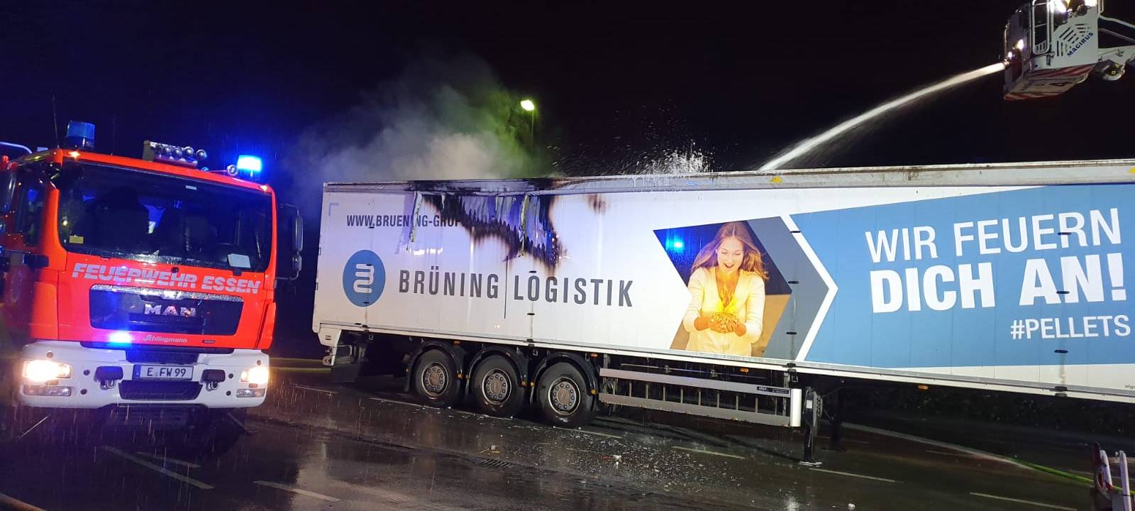 Das Bild zeigt den qualmenden LKW-Anhänger. Die Feuerwehr löscht mit einem dicken Schlauch.