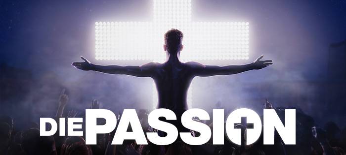 Teaserbild für die Show Passion; abgedunkelte Person steht mit ausgebreiteten Armen vor einem weiß leuchtenden Kreuz