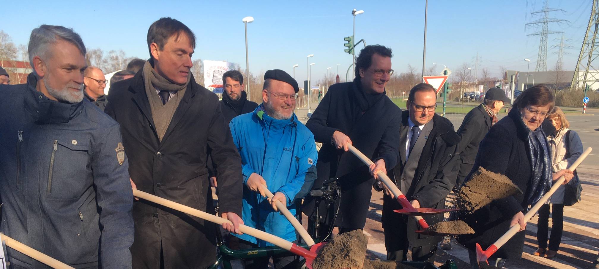 Personen schaufeln Erde mit Spaten aus einem Lastenrad.