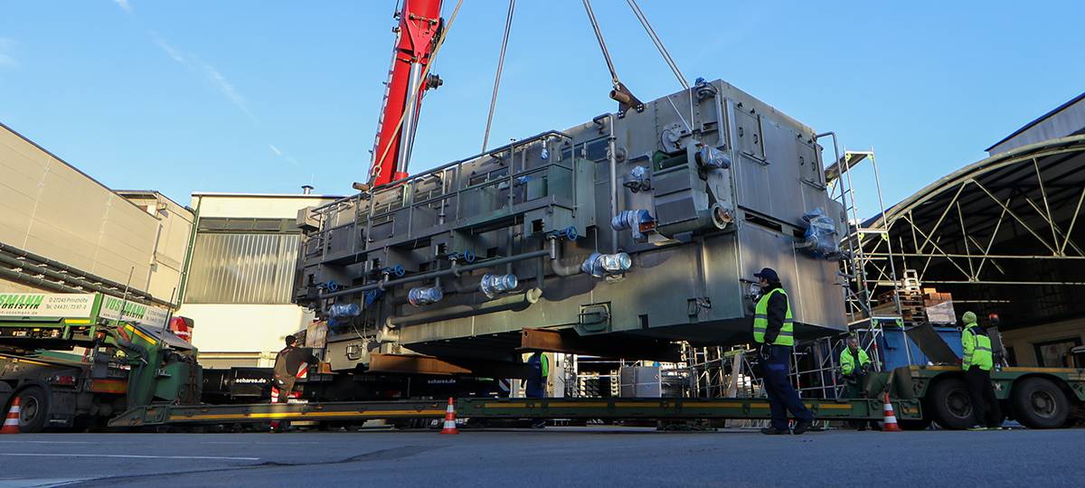 Die neue Abfüllanlage ist ein rechteckiger Klotz mit vielen Anschlüssen. Hier wird sie gerade vom Schwertransporter gehoben.