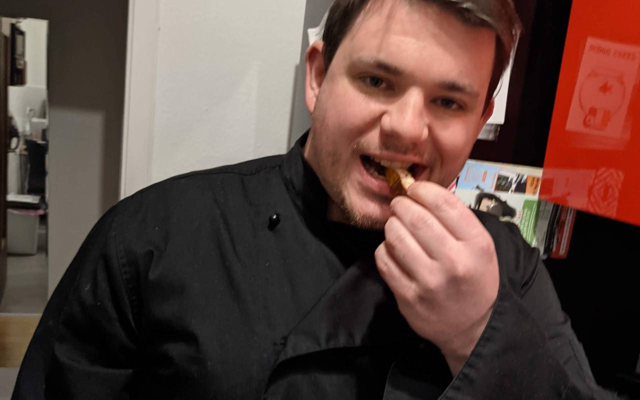 Tobi Bitter testet Essen und trägt schwarze Kochjacke