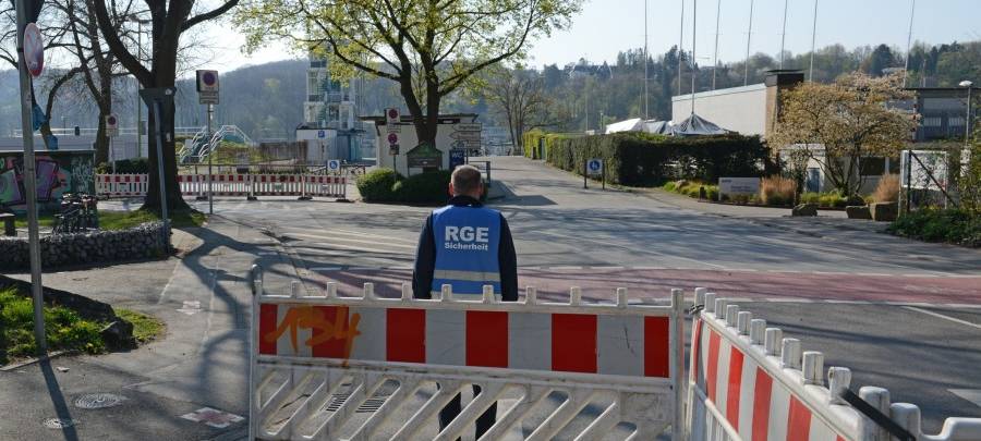 Ein Mitarbeiter der RGE Servicegesellschaft Essen mbH steht am abgesperrten Einmündungsbereich an der Freiherr-vom-Stein-Straße zum Parkplatz am Regattaturm.