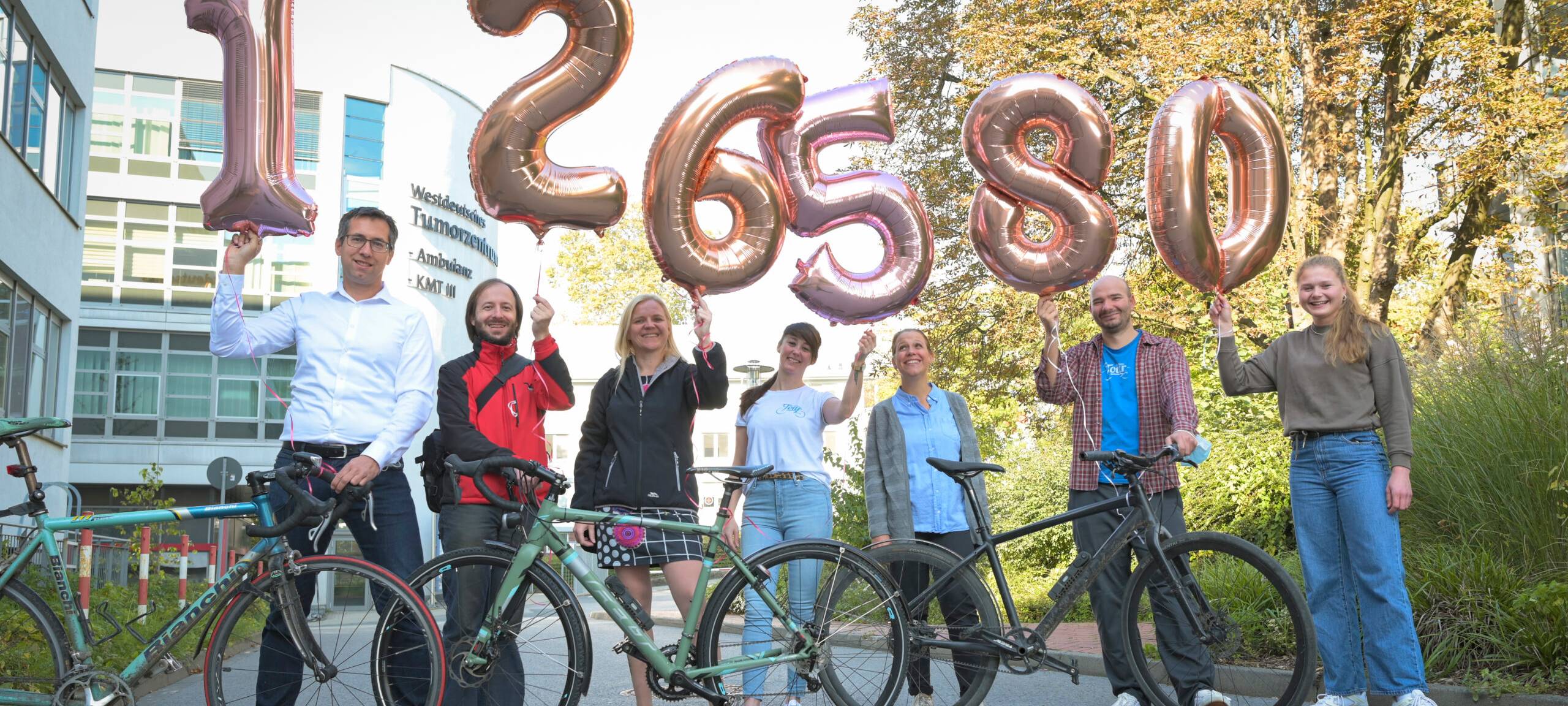 Die Organisatoren freuen sich über das besondere Spendenergebnis der 16. Sarkomtour. Sie halten Luftballons mit der Spendensumme in die Höhe.