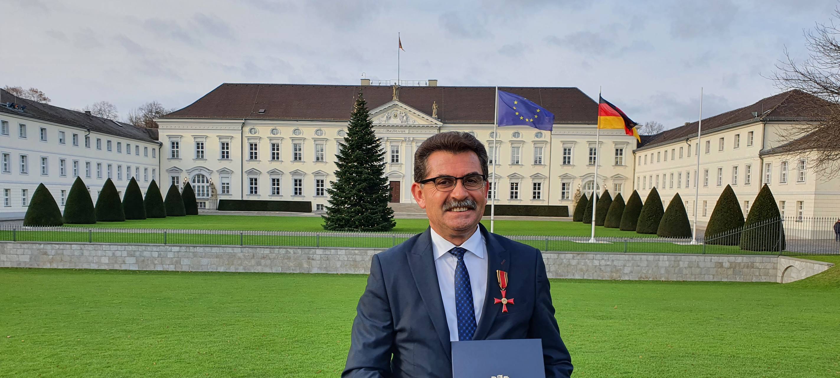 Turgay Tahtabas zeigt sein Bundesverdienstkreuz vor dem Schloss Bellevue in Berlin.