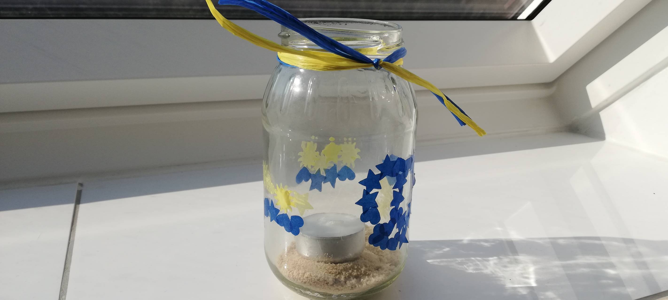 Die Friedenslichter für die Ukraine sind bunt beklebt, dieses in den Farben blau und gelb.