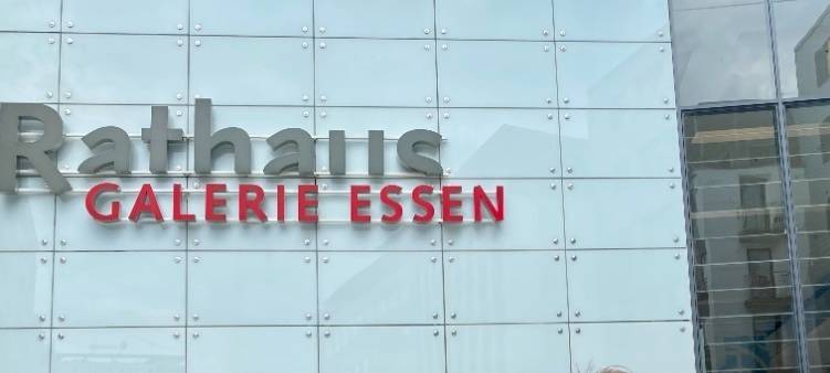 Rathaus Galerie Centermanager Frederik Westerhoff steht vor dem Haupteingang und zeigt auf das Einkaufszentrum