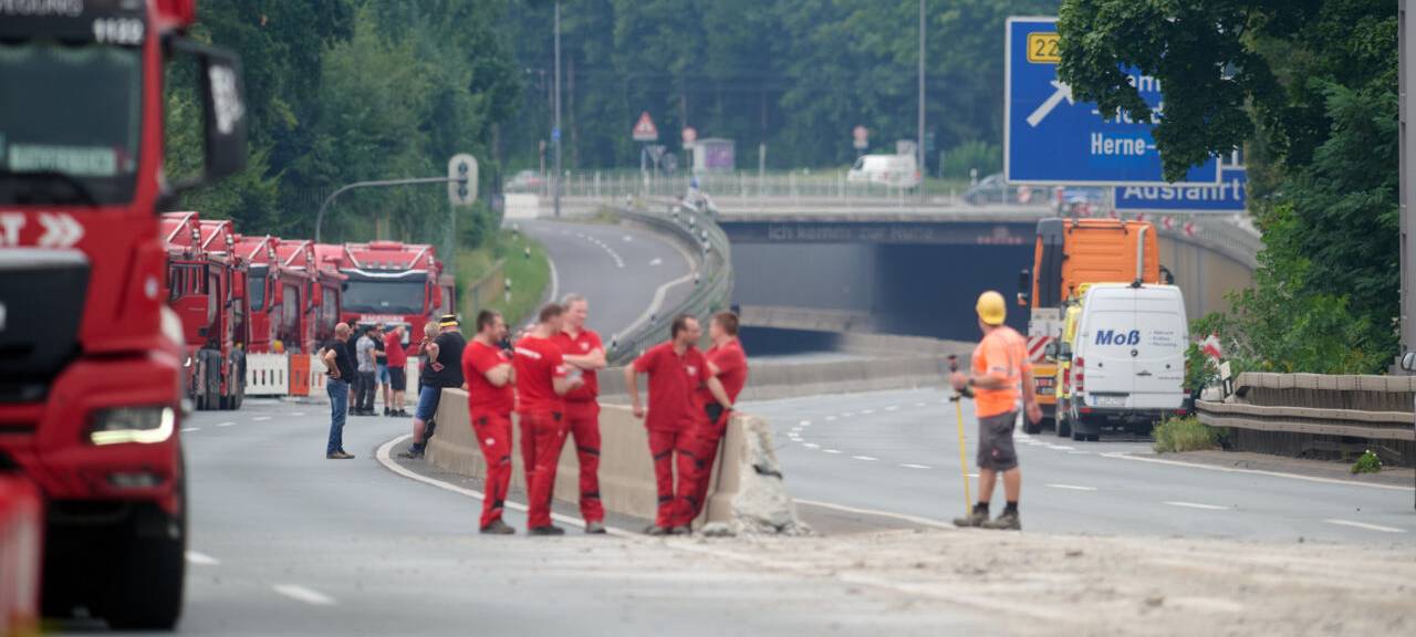Arbeiter stehen auf der gesperrten A40-Autobahn im Ruhrgebiet.