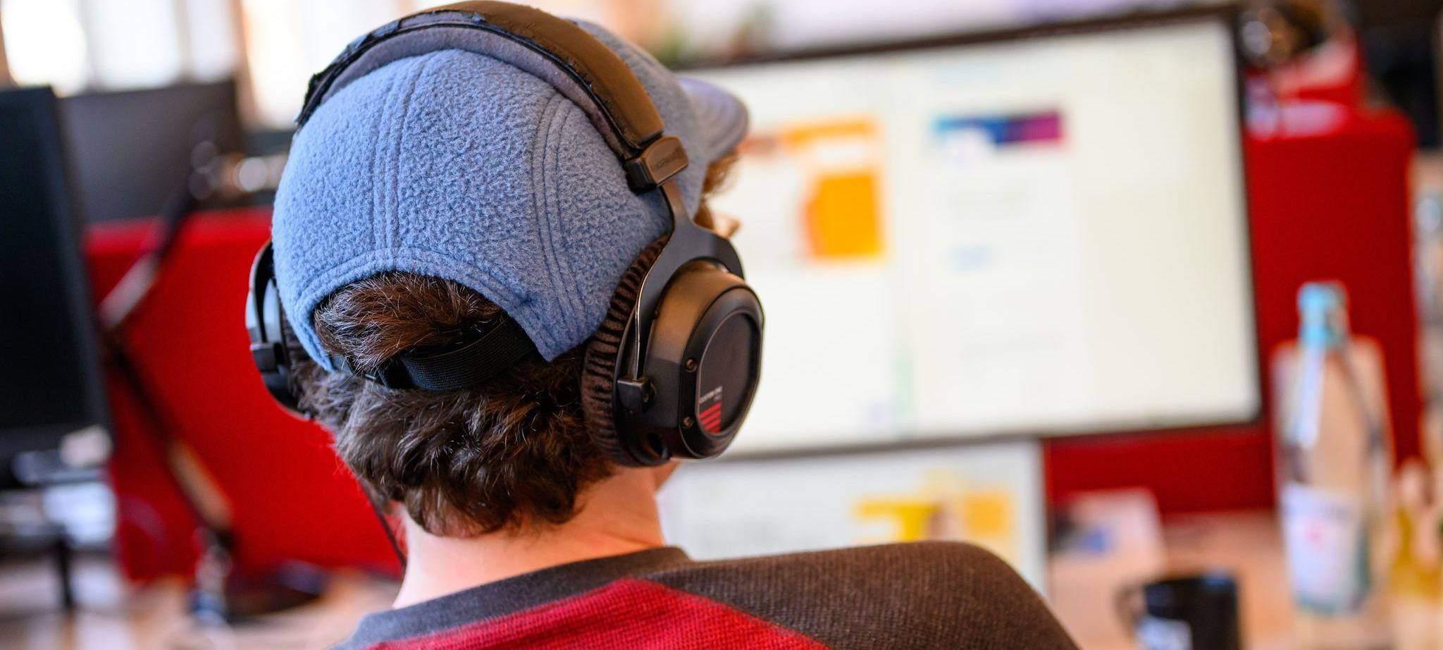 Ein Mitarbeiter mit Kopfhörern vor einem Computer-Bildschirm