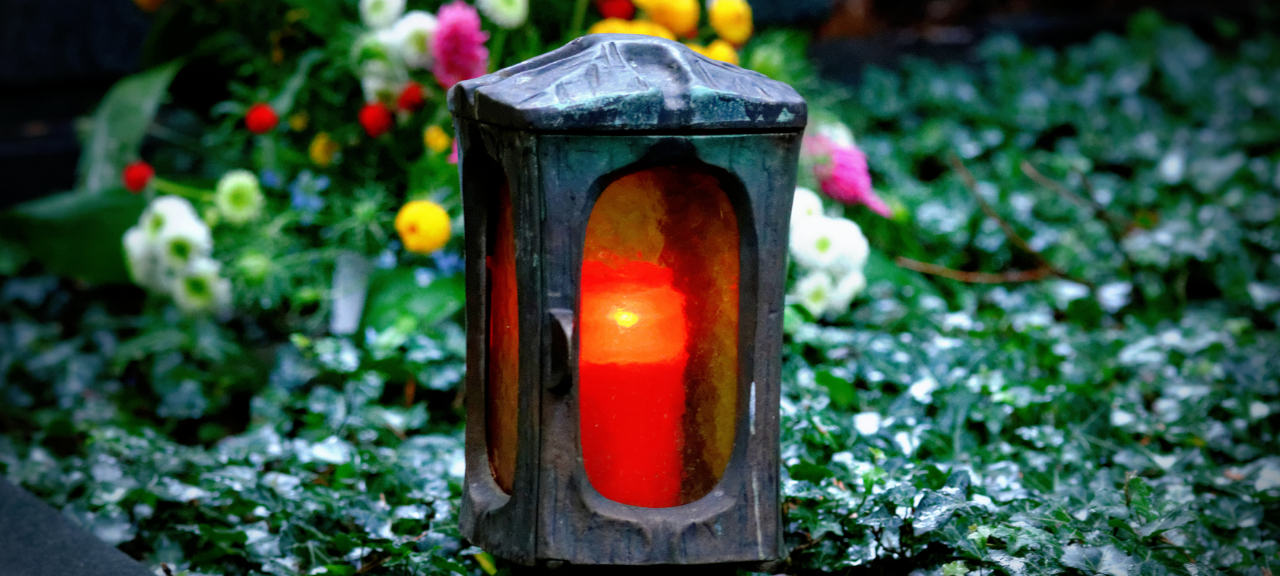 Symbolbild: Grablichter mit angezündeter roter Kerze.