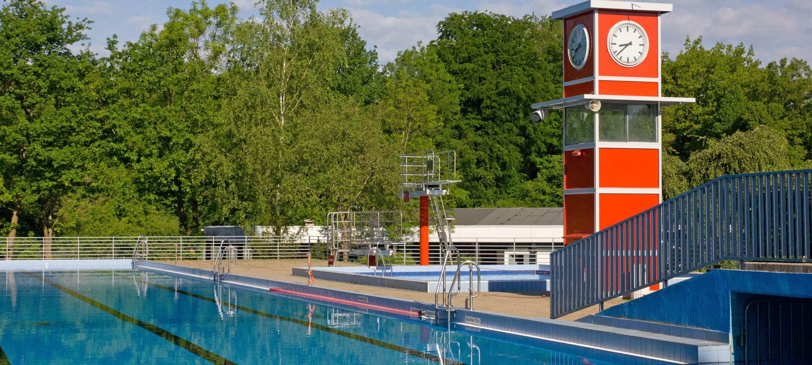 Das Sportbecken im Freibad Oststadtbad in Essen Freisenbruch mit dem typischen roten rechteckigen Turm mit Uhr.