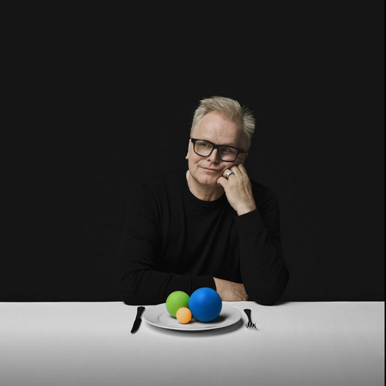 Herbert Grönemeyer sitzt an einem Tisch mit einem Teller vor sich, auf dem drei farbige Bälle liegen.